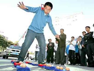 Zhang Xingquan pulling a car with his ears while walking on eggs